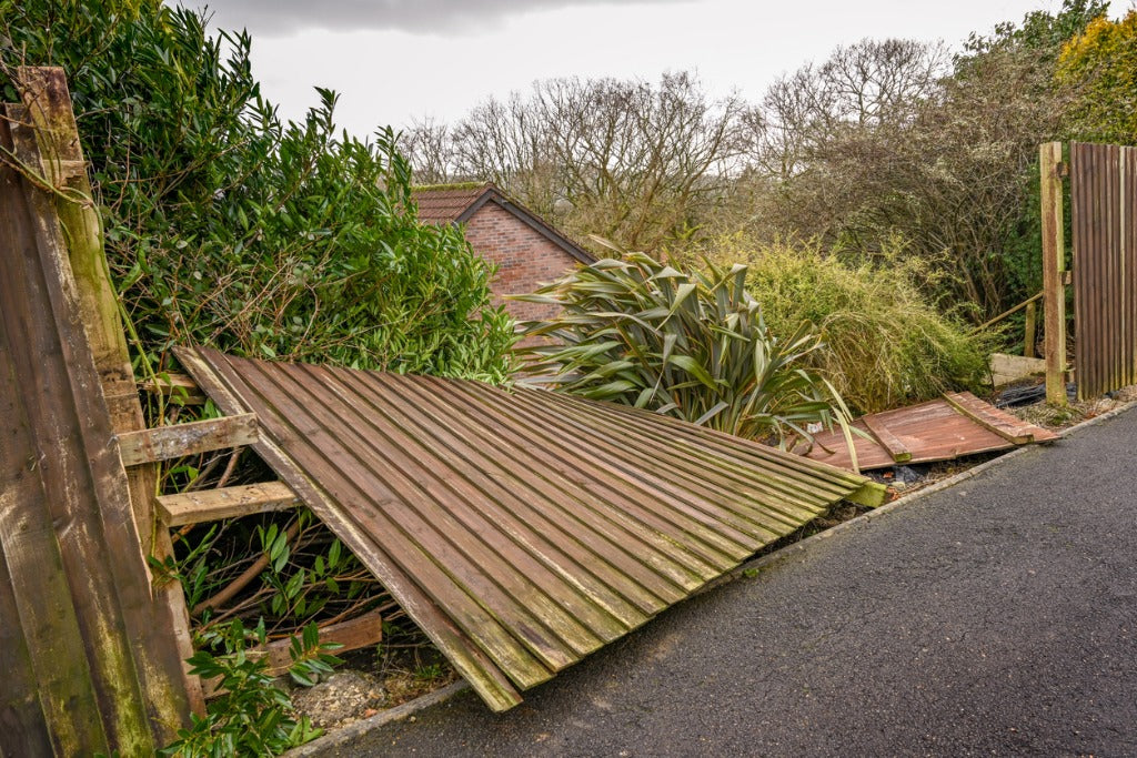 Wood privacy fence section blown down by Kansas wind in a Wichita-area yard — the kind of storm-driven fence damage a wind-resistant fence is designed to prevent